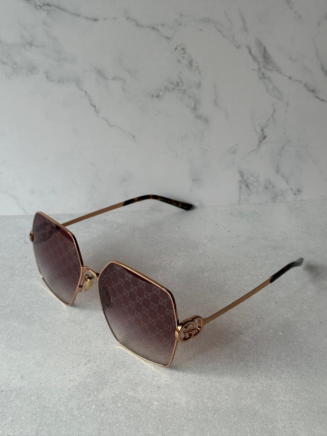Oversized rose gold metal sunglasses with dark lenses and GG-style logo temple arms