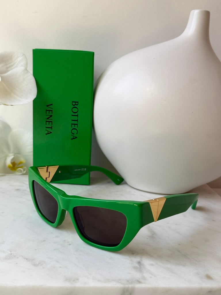 Green cat-eye sunglasses with dark lenses on display, with Bottega Veneta box