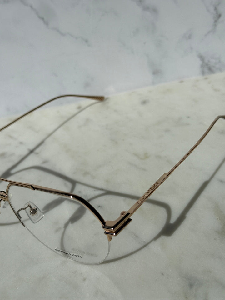 Gold aviator eyeglass frame detail with clear lenses and hinge