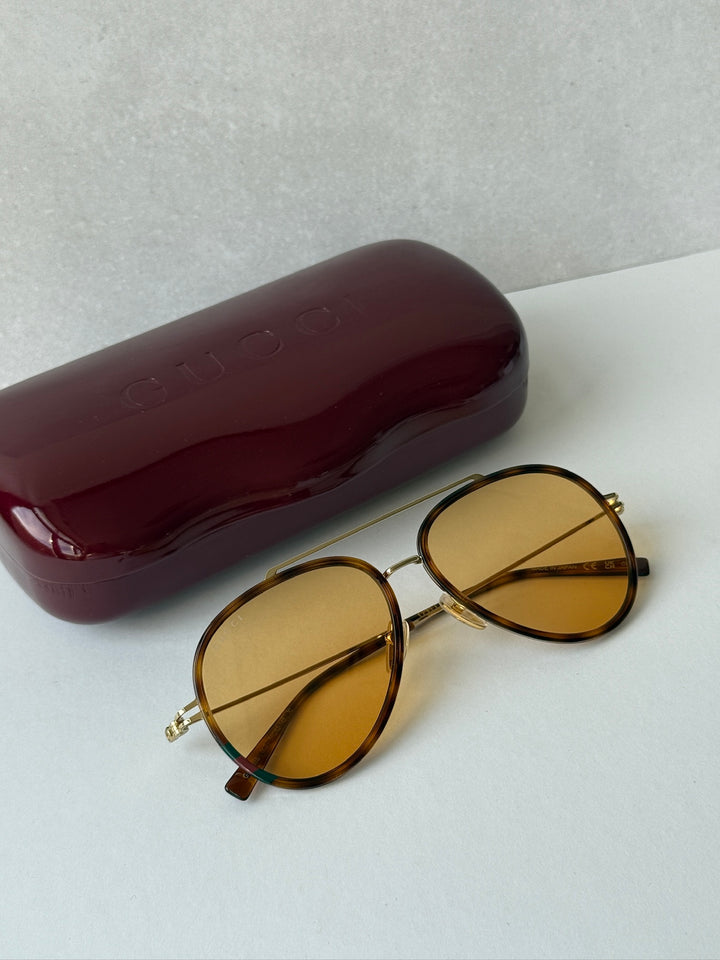 Gucci aviator sunglasses with oval brown frames and amber tinted lenses, gold accents