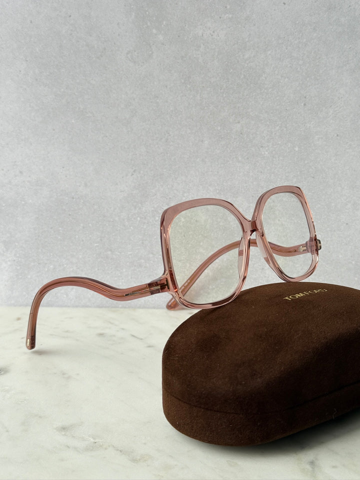 Pink oversized blue-light glasses frames with curved temples, resting on case