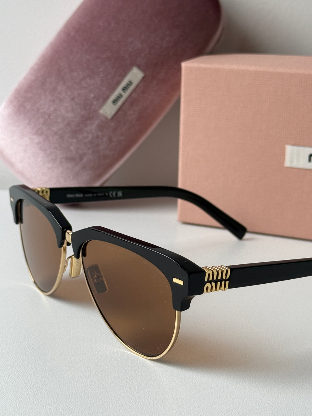 Miu Miu black cat-eye sunglasses close-up with brown lenses and gold hinge detail