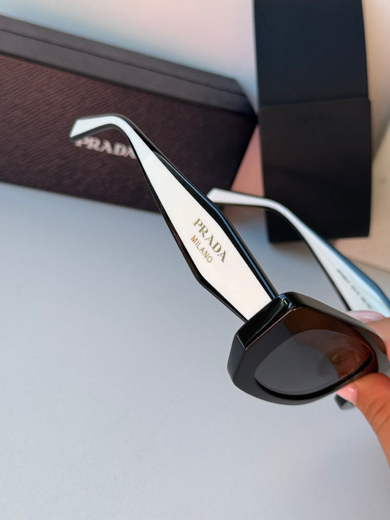 Prada black sunglasses with white temples and dark lenses, close-up detail.