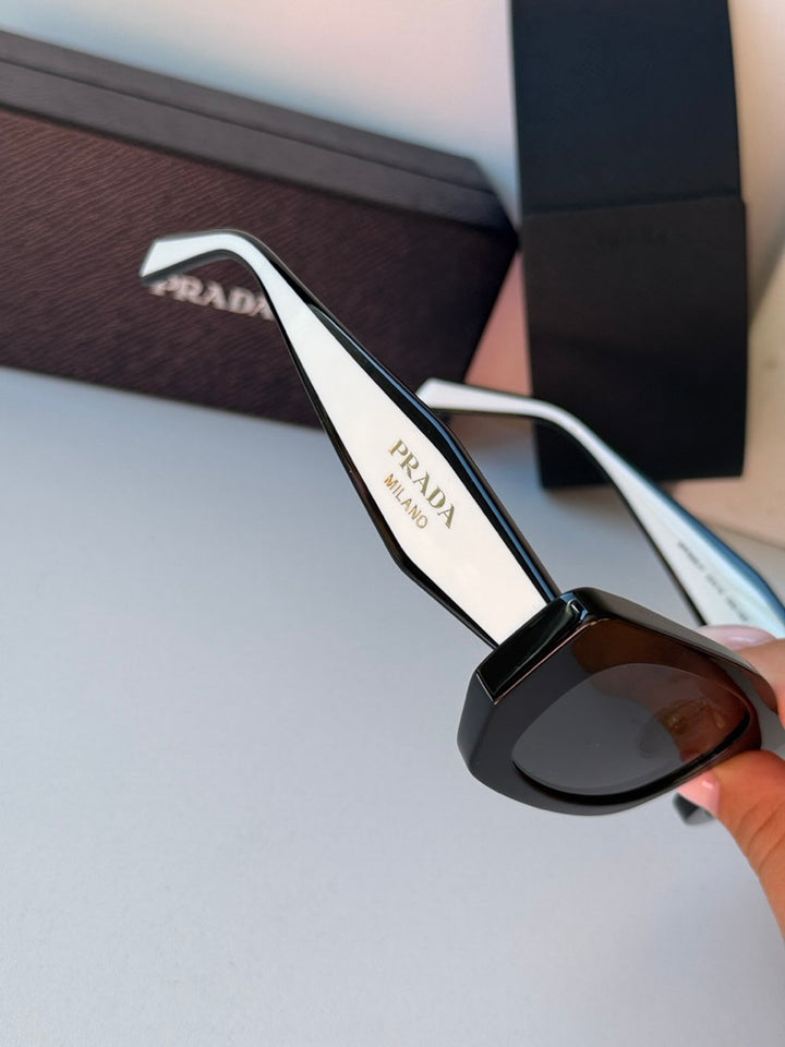 Prada black sunglasses with white temples and dark lenses, close-up detail.