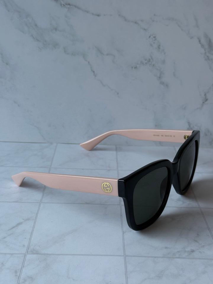 Pink and black cat-eye sunglasses with dark lenses, Gucci logo on temple