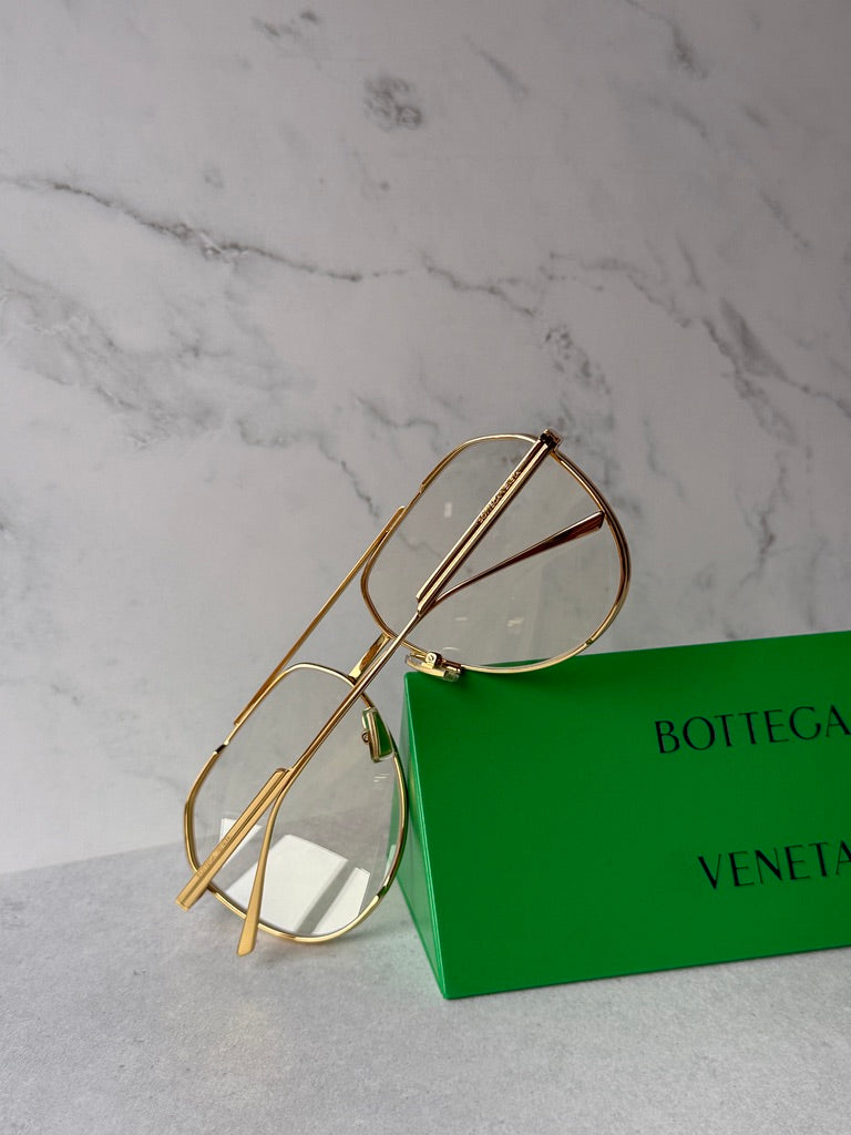 Gold aviator sunglasses close-up with green-tinted lenses and hinge detail