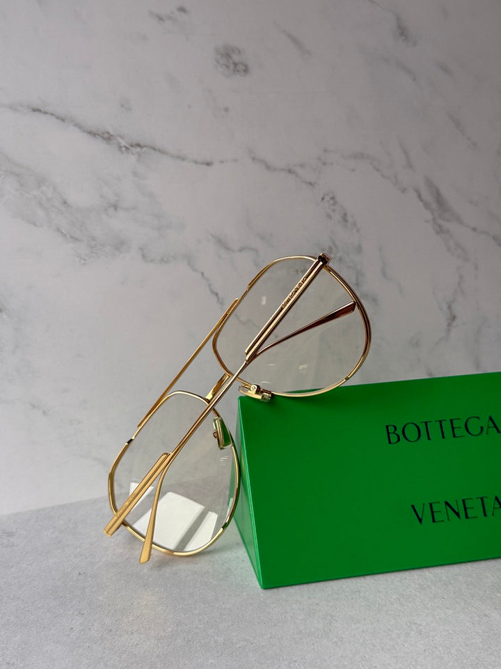 Gold aviator sunglasses close-up with green-tinted lenses and hinge detail