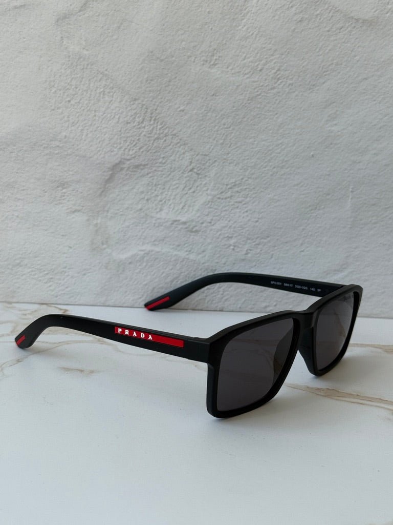 Black polarized sunglasses with dark lenses; low angle shows red trim on arms