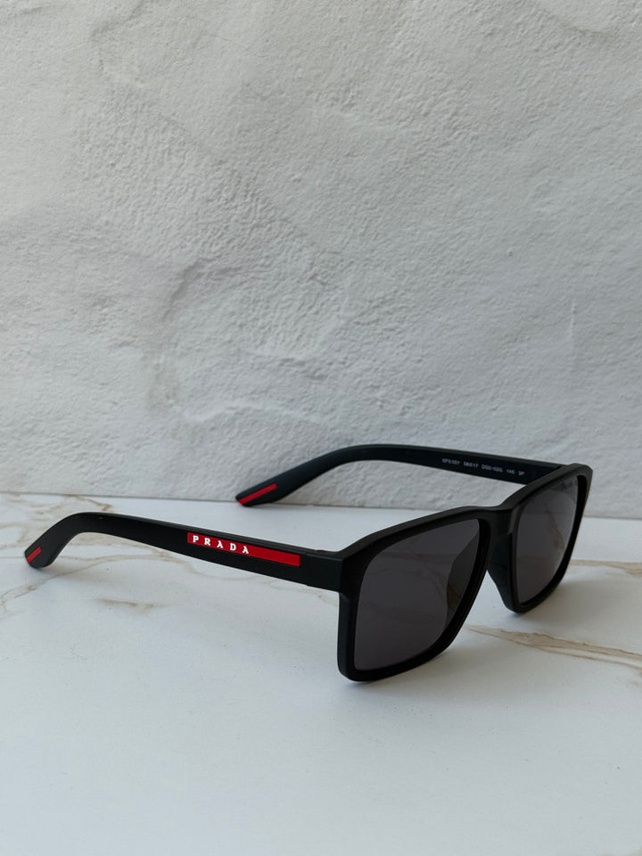 Black polarized sunglasses with dark lenses; low angle shows red trim on arms