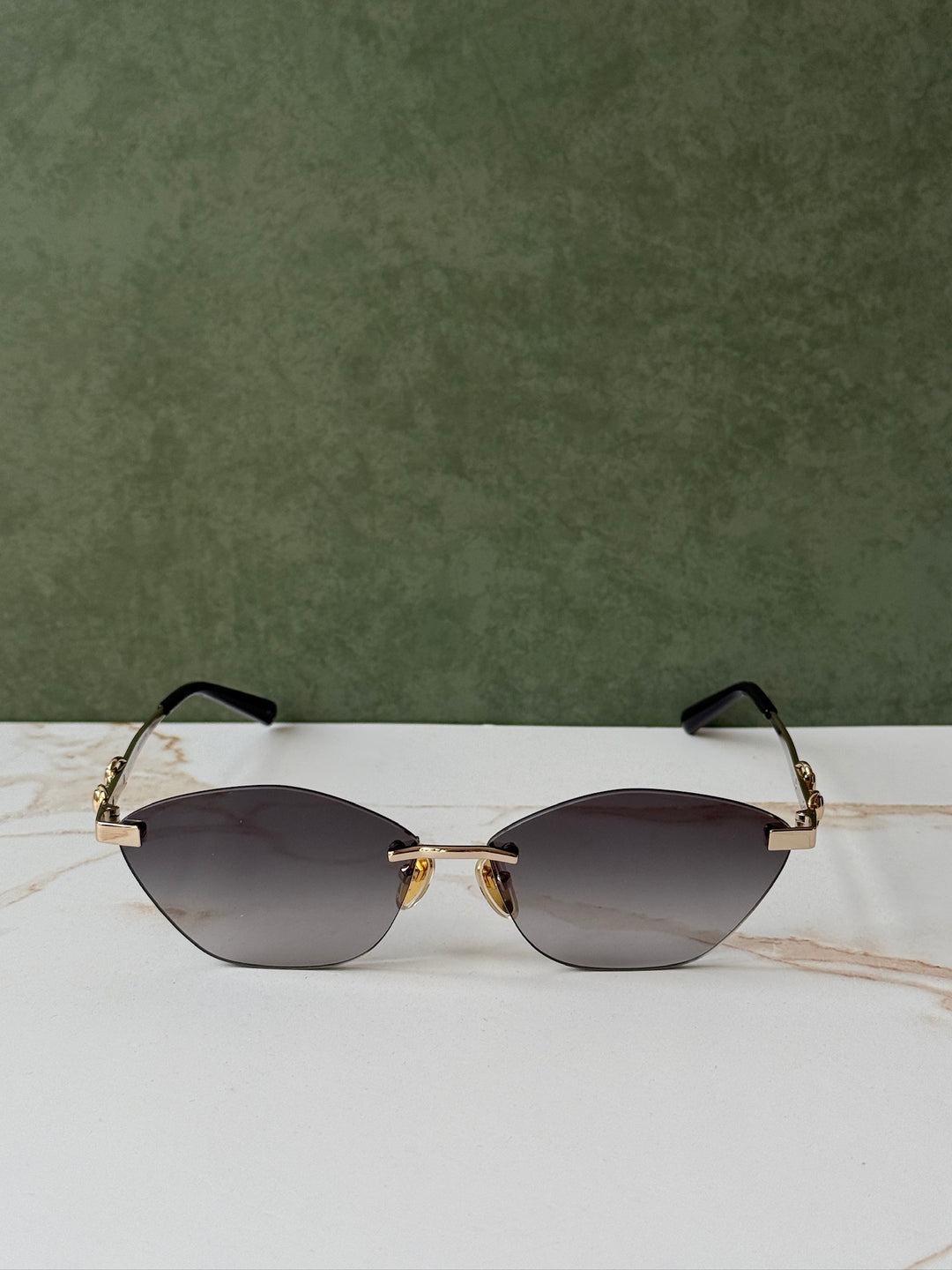 Gucci cat-eye sunglasses with gold frame, dark lenses, and horsebit bridge, straight view