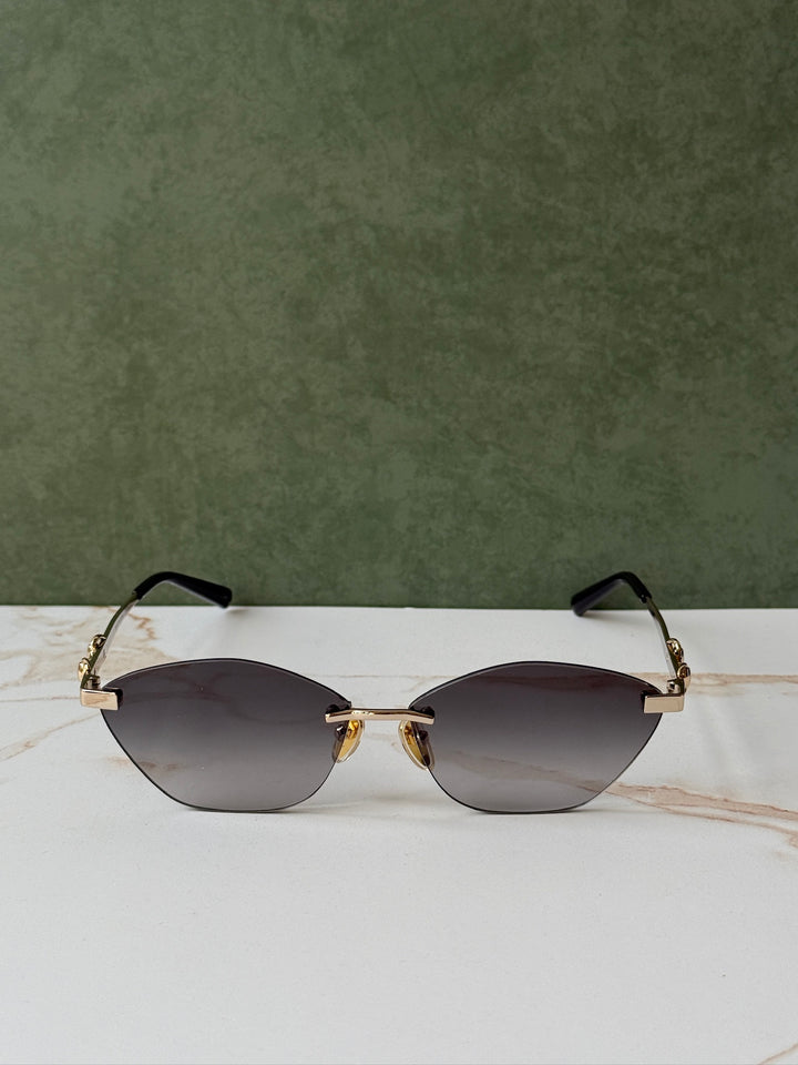 Gucci cat-eye sunglasses with gold frame, dark lenses, and horsebit bridge, straight view