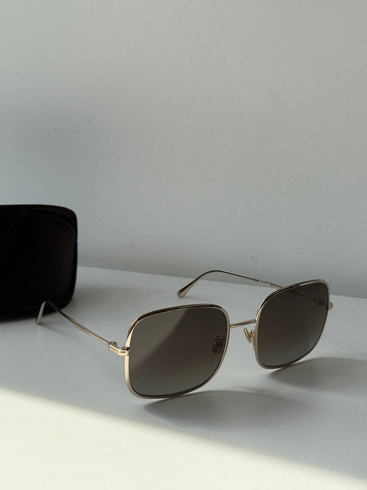Gold square sunglasses with dark lenses on white surface.