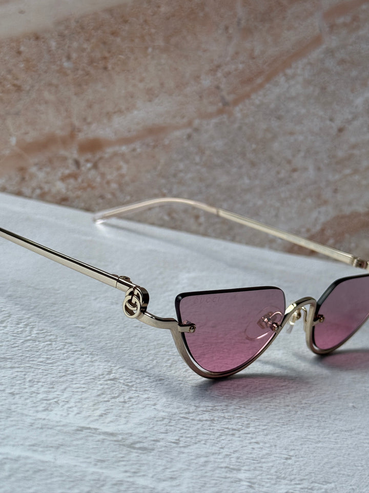Gucci half-rim sunglasses close-up, gold frame and pink lenses