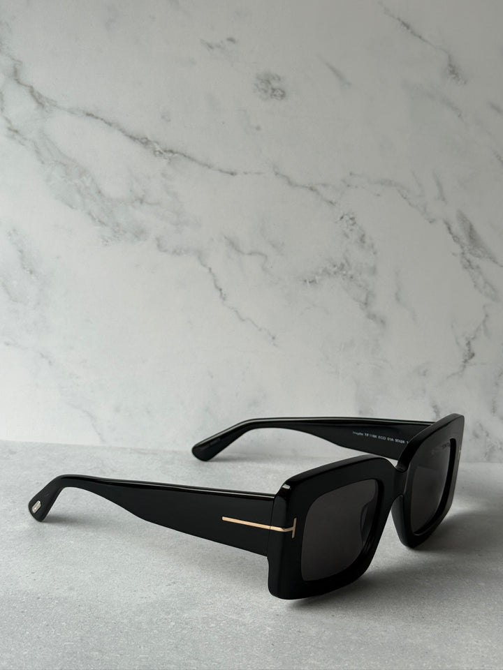 Black square sunglasses side view with dark lenses and gold bar detail
