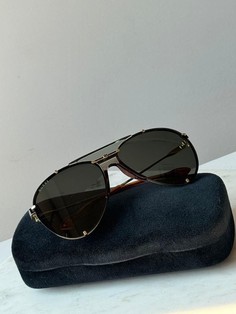 Gucci aviator logo sunglasses on dark blue velvet case, dark lenses and gold-tone frame