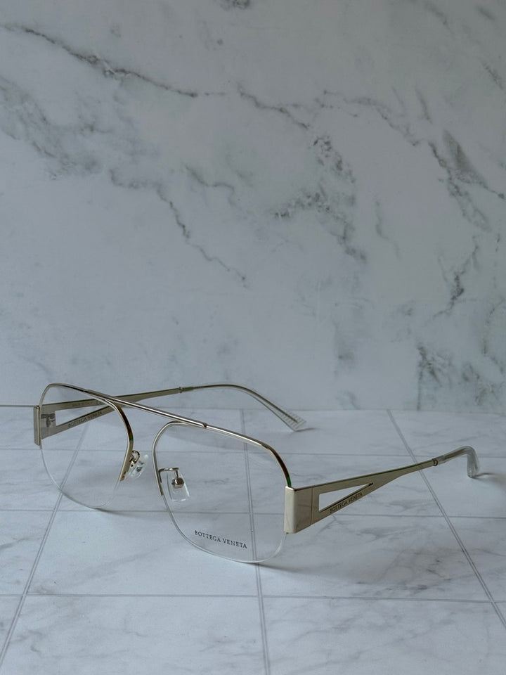 Gold-tone aviator eyeglass frames with clear lenses and angular temple details