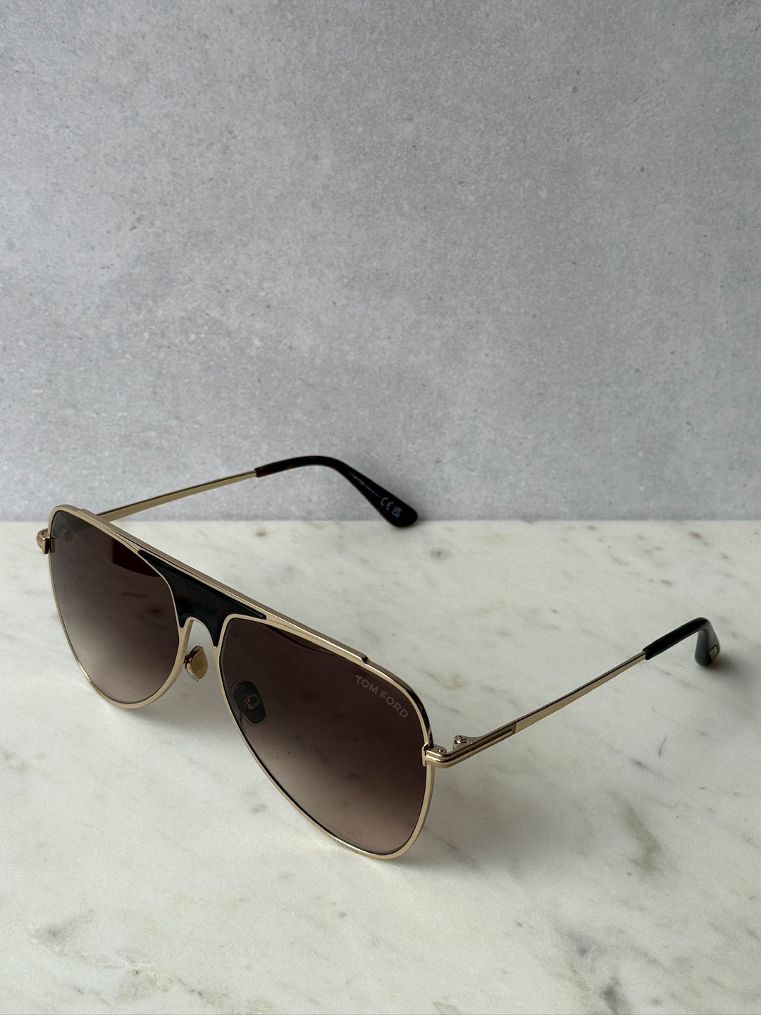 Pilot sunglasses with rose gold metal frame and dark brown lenses, black nose pads