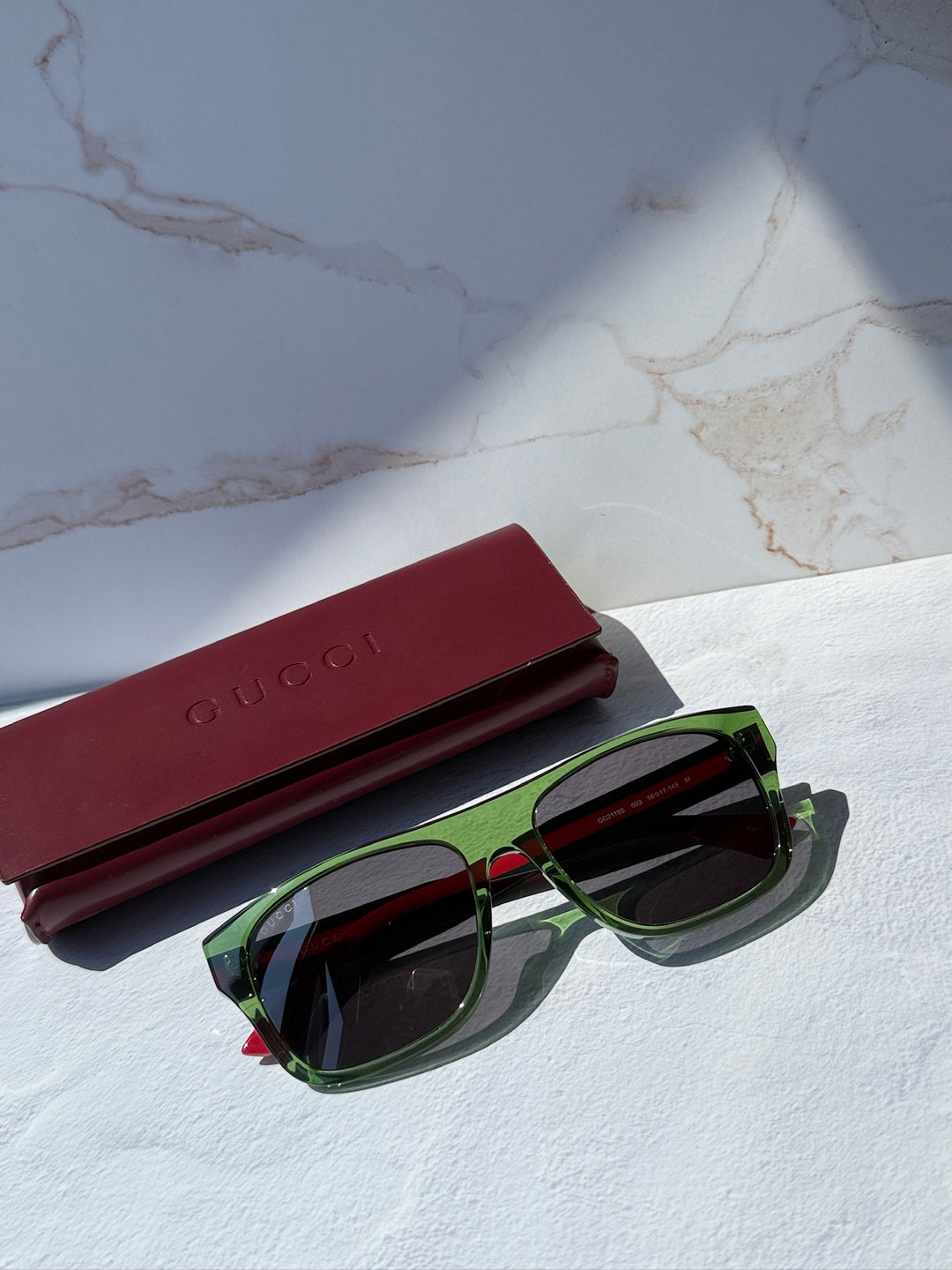 Gucci sunglasses with green frame, dark lenses, red temple stripes and case.