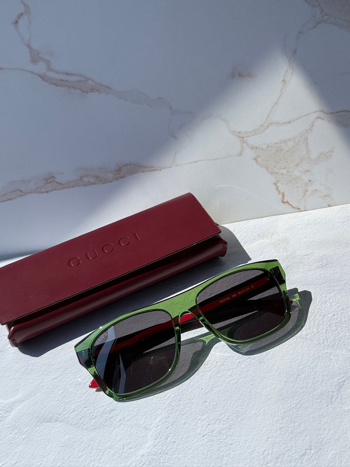 Gucci sunglasses with green frame, dark lenses, red temple stripes and case.