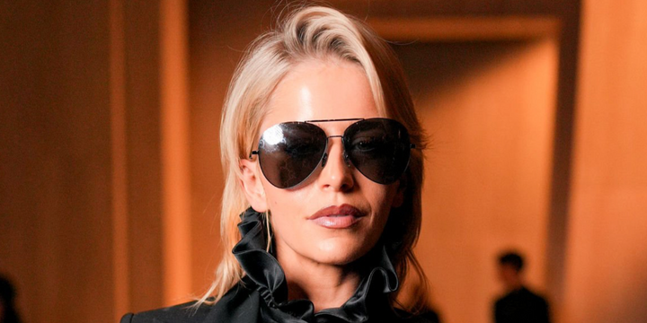 Woman wearing black aviator sunglasses with dark lenses and GG logo patterned frame