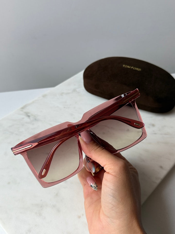 Pink square sunglasses held in hand, temple hinge and brown gradient lenses
