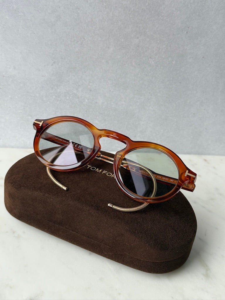 Brown tortoise round sunglasses resting on a brown case with gold-tone temples