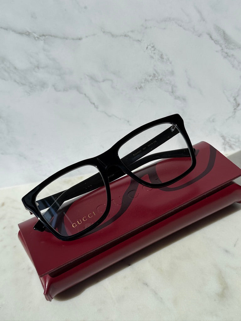 Black rectangular eyeglass frames with clear lenses and Gucci branding on temples