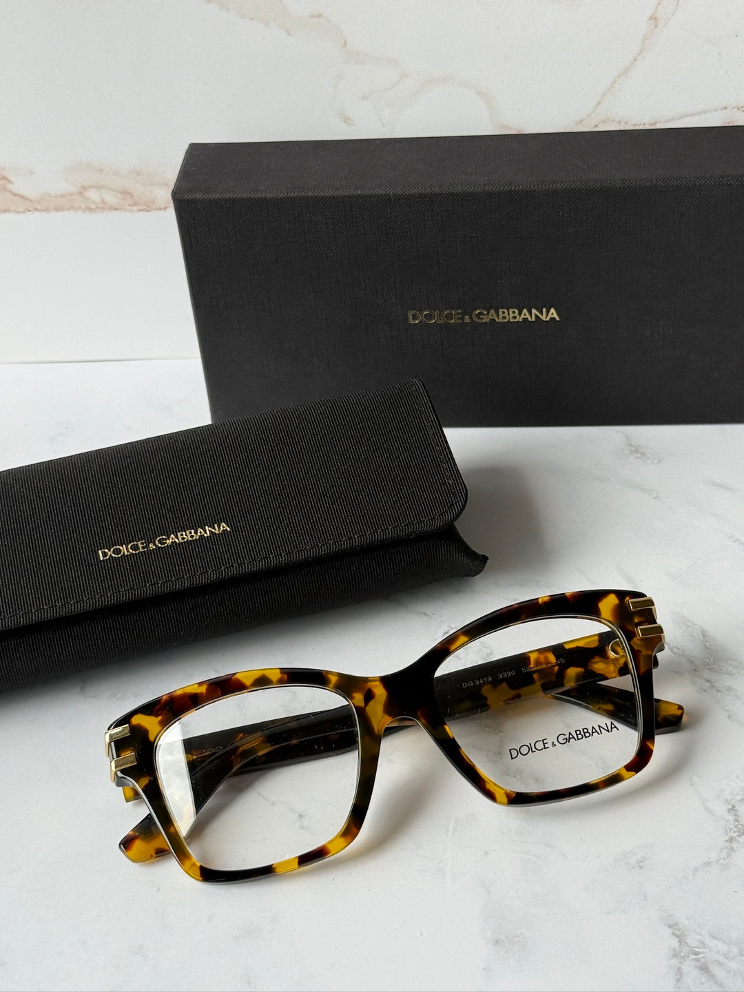 Tortoise-brown rectangular eyeglass frames with clear lenses and gold DG logo