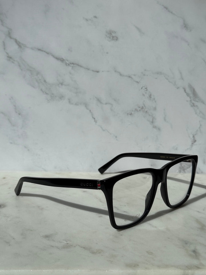 Black rectangular eyeglass frames with clear lenses and Gucci mark on temple
