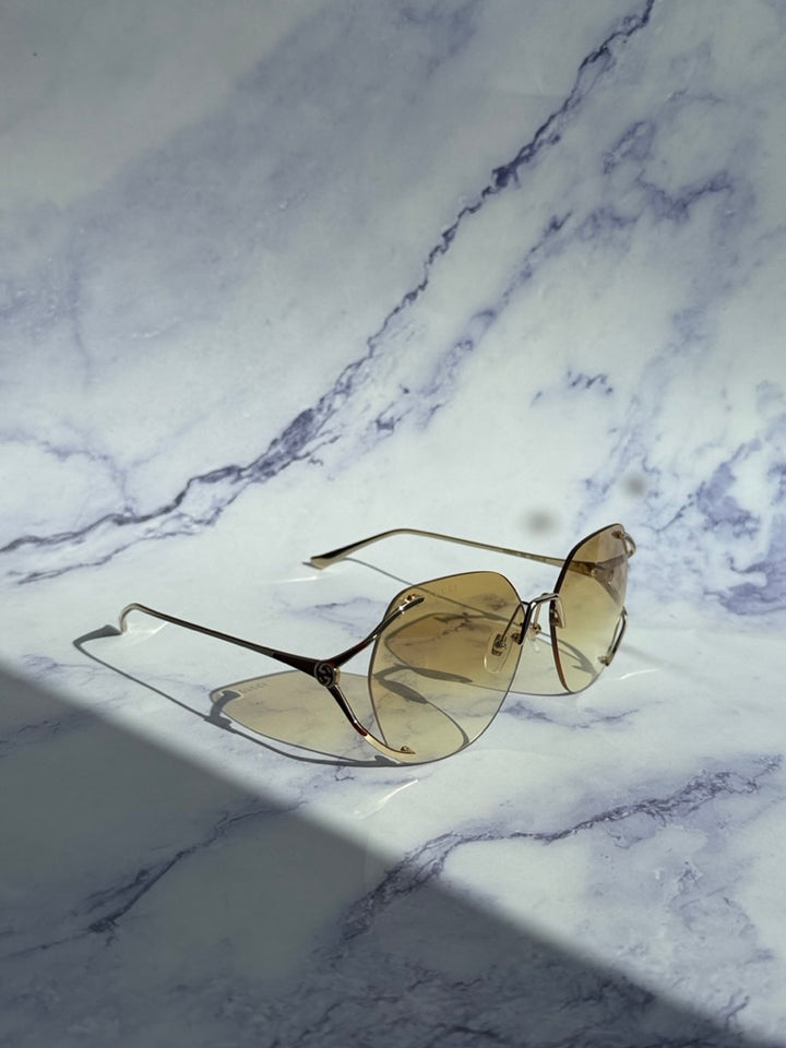 Gucci rimless sunglasses, side view, gold frame and yellow lenses