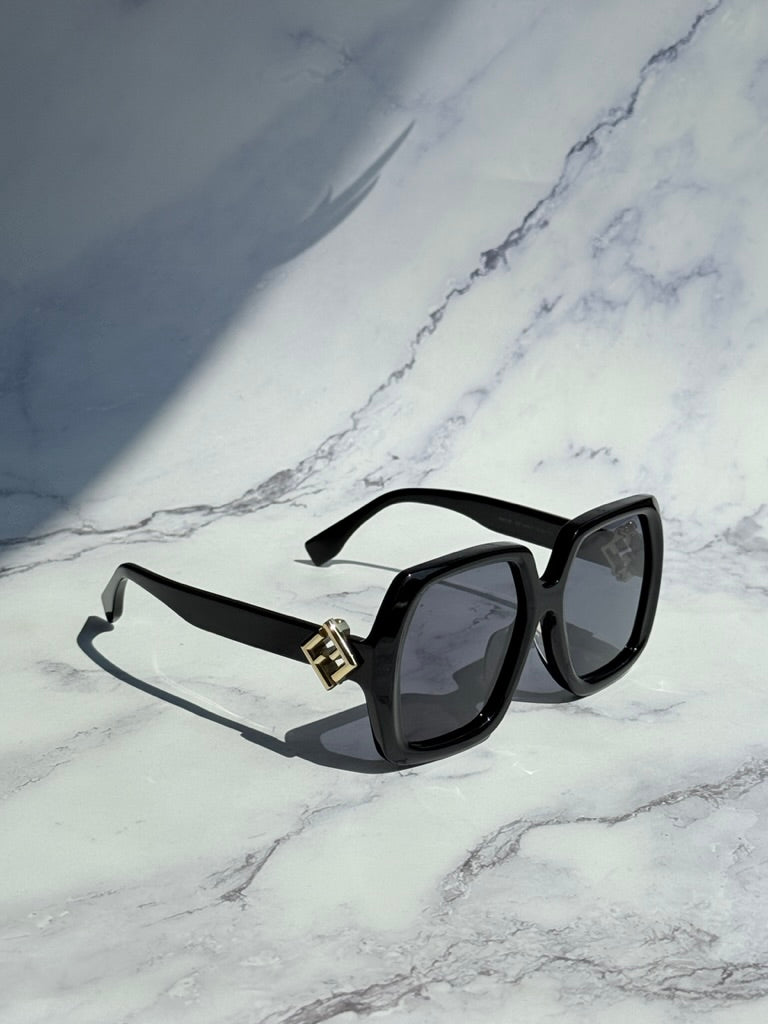Black square sunglasses with dark lenses and gold logo bridge, three-quarter angle