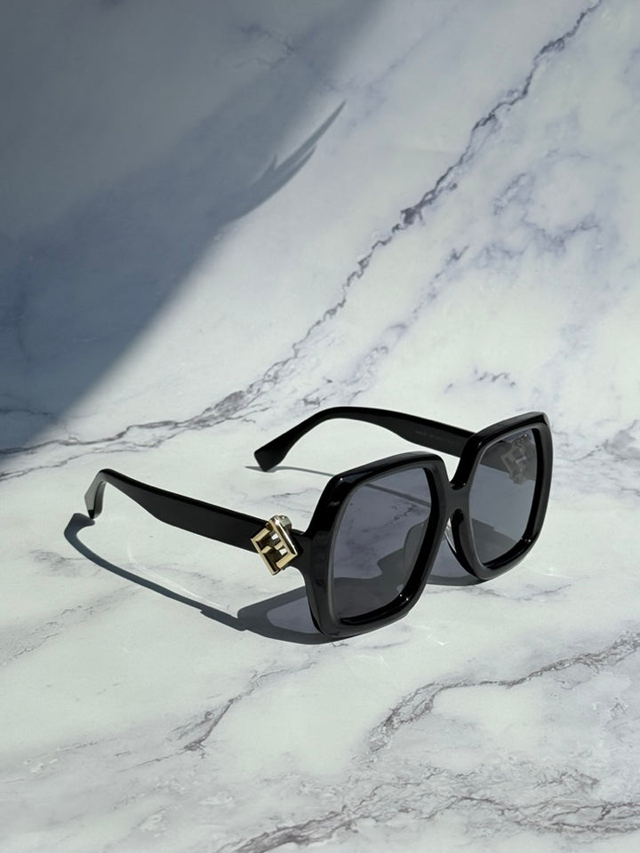 Black square sunglasses with dark lenses and gold logo bridge, three-quarter angle