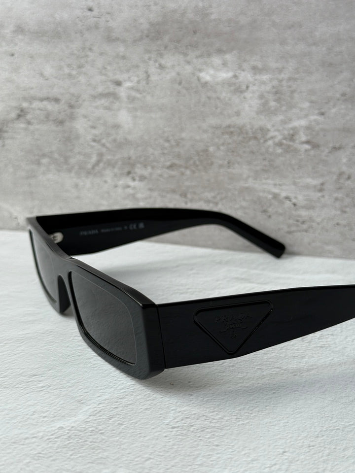 Prada black rectangular sunglasses with dark lenses, angled side view.