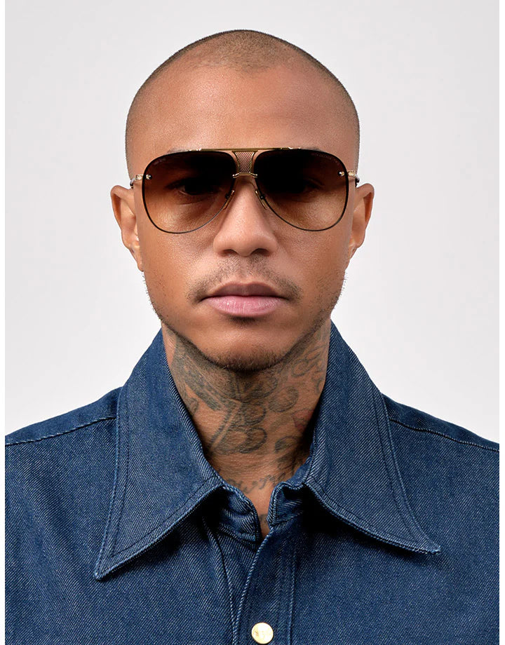 Aviator sunglasses on a person, dark lenses with gold frame and thin arms