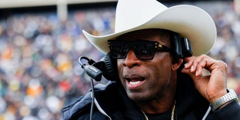 Man wearing black sunglasses with gold-tone accents and dark gradient lenses
