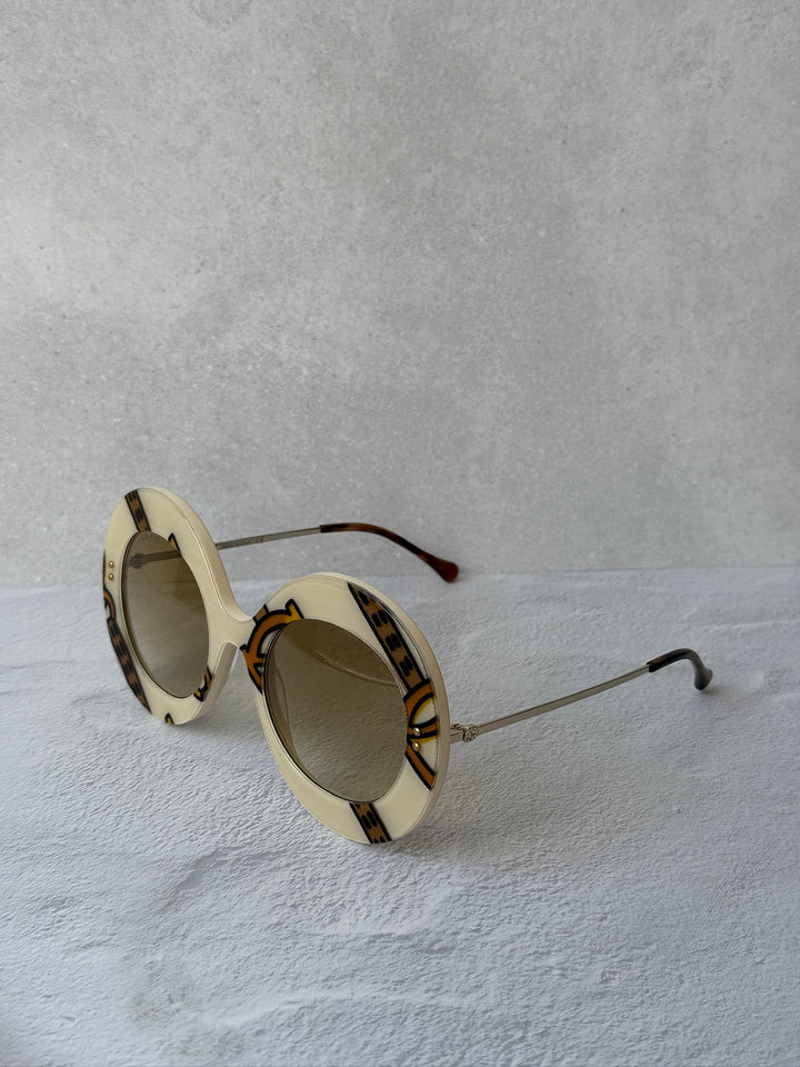 Round sunglasses with cream frames, brown lenses, and tortoise-style side band.