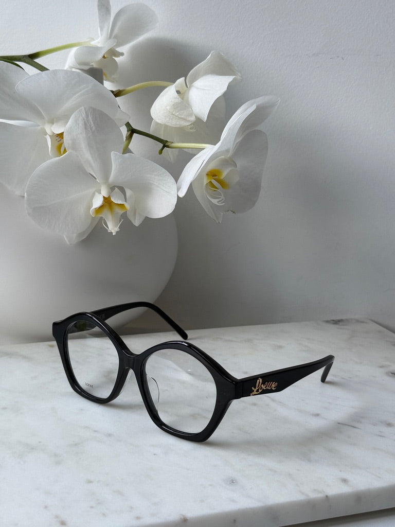 Black curvy eyeglass frames with rounded lenses, gold Loewe logo across temple