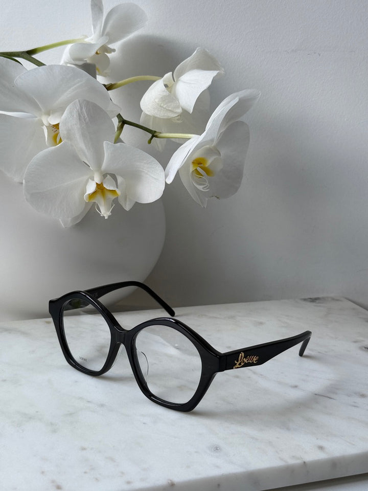 Black curvy eyeglass frames with rounded lenses, gold Loewe logo across temple