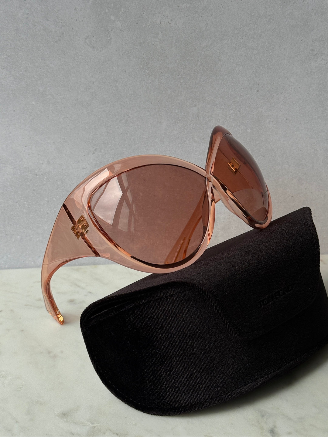 Oversized mask sunglasses with pink frame and brown tinted lenses, with black case.