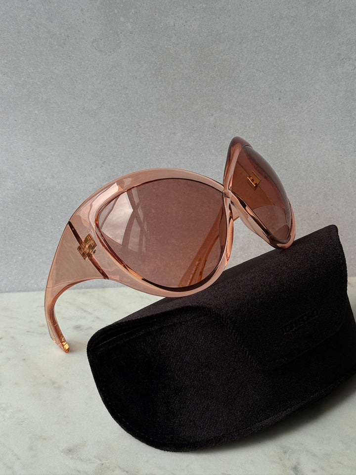 Oversized mask sunglasses with pink frame and brown tinted lenses, with black case.