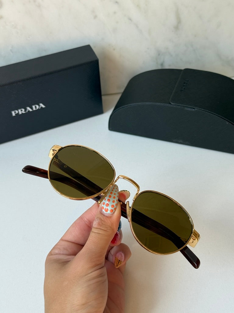 Prada round sunglasses, gold frame with dark brown lenses and brown temple tips, held
