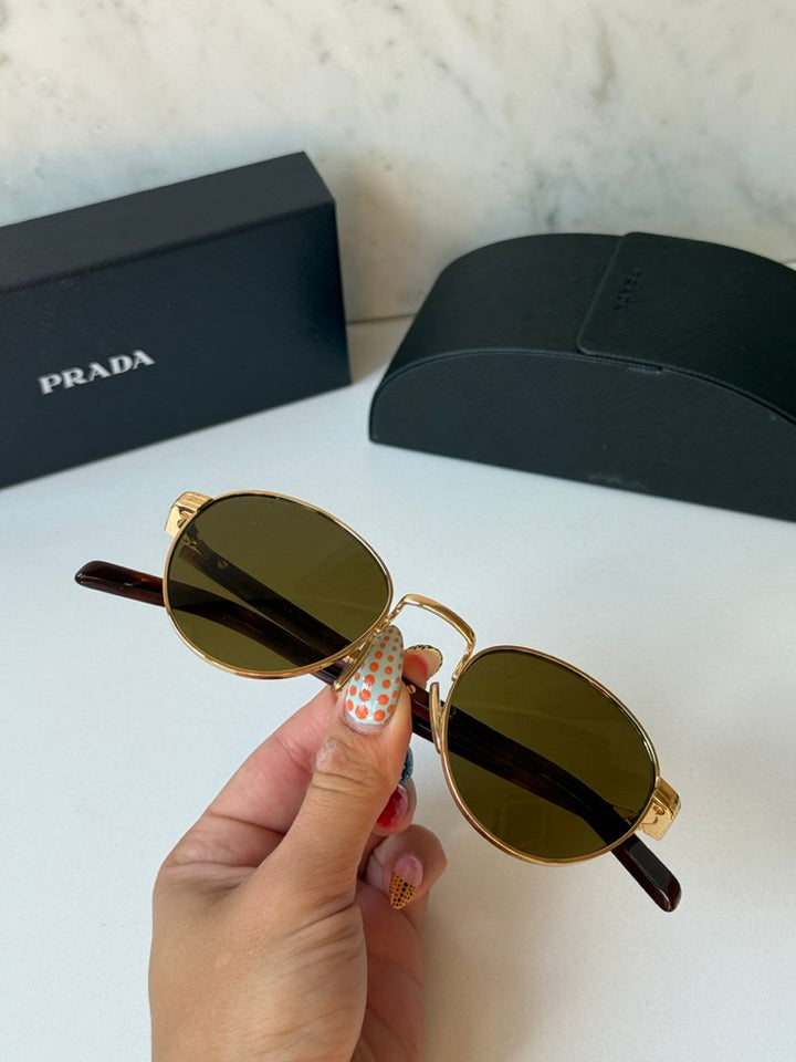Prada round sunglasses, gold frame with dark brown lenses and brown temple tips, held