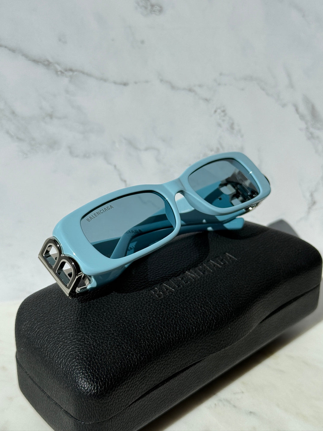 Balenciaga baby blue sunglasses with logo hardware and dark tinted lenses