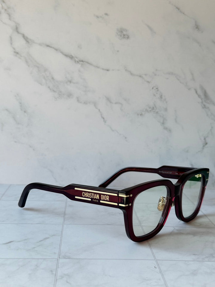 Burgundy eyeglass frames with green-tinted lenses and Dior logo on temple