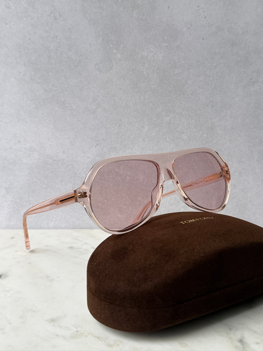 Pink aviator sunglasses with rose-tinted lenses and metal frame, on a case