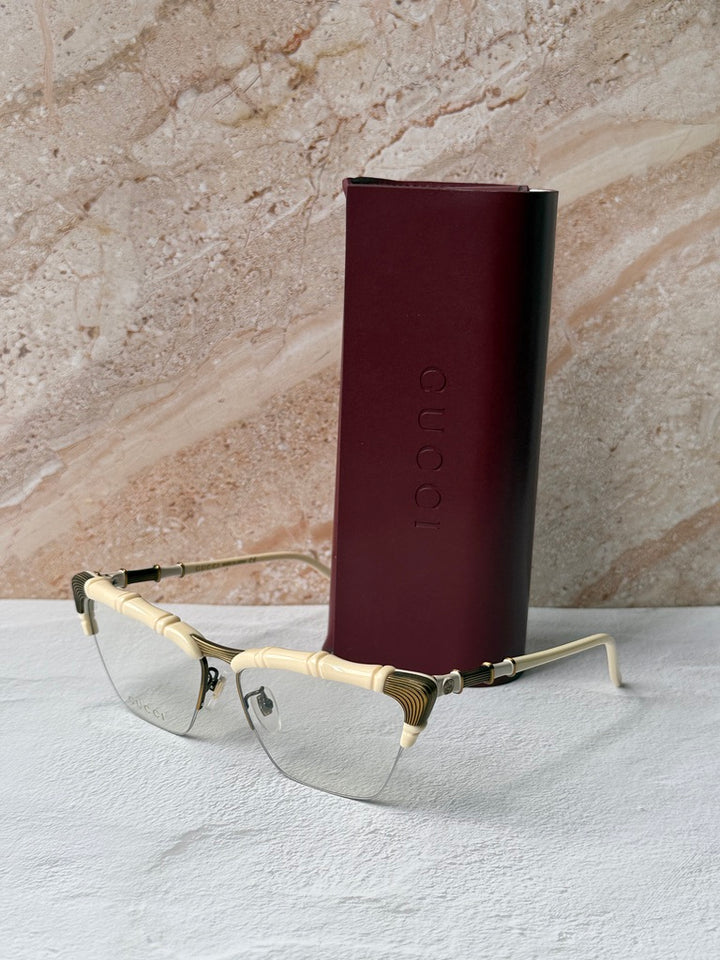 Gucci ivory cat-eye eyeglass frames with gold bamboo temples, angled view