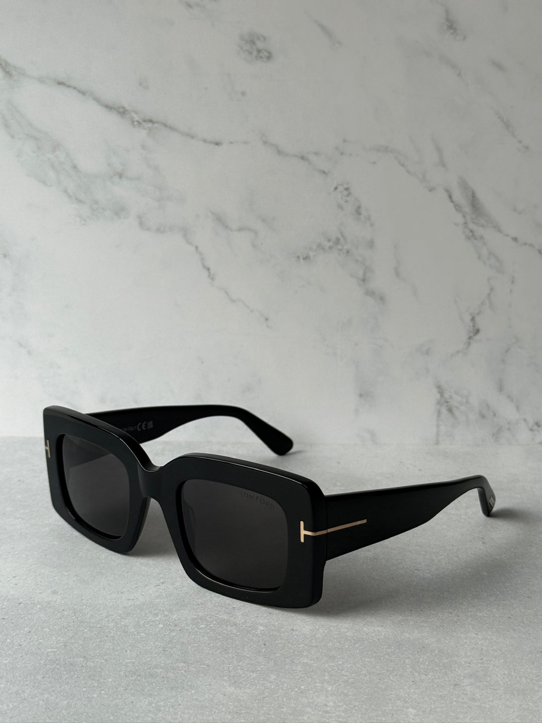 Black square sunglasses with dark lenses and gold-tone bar accents