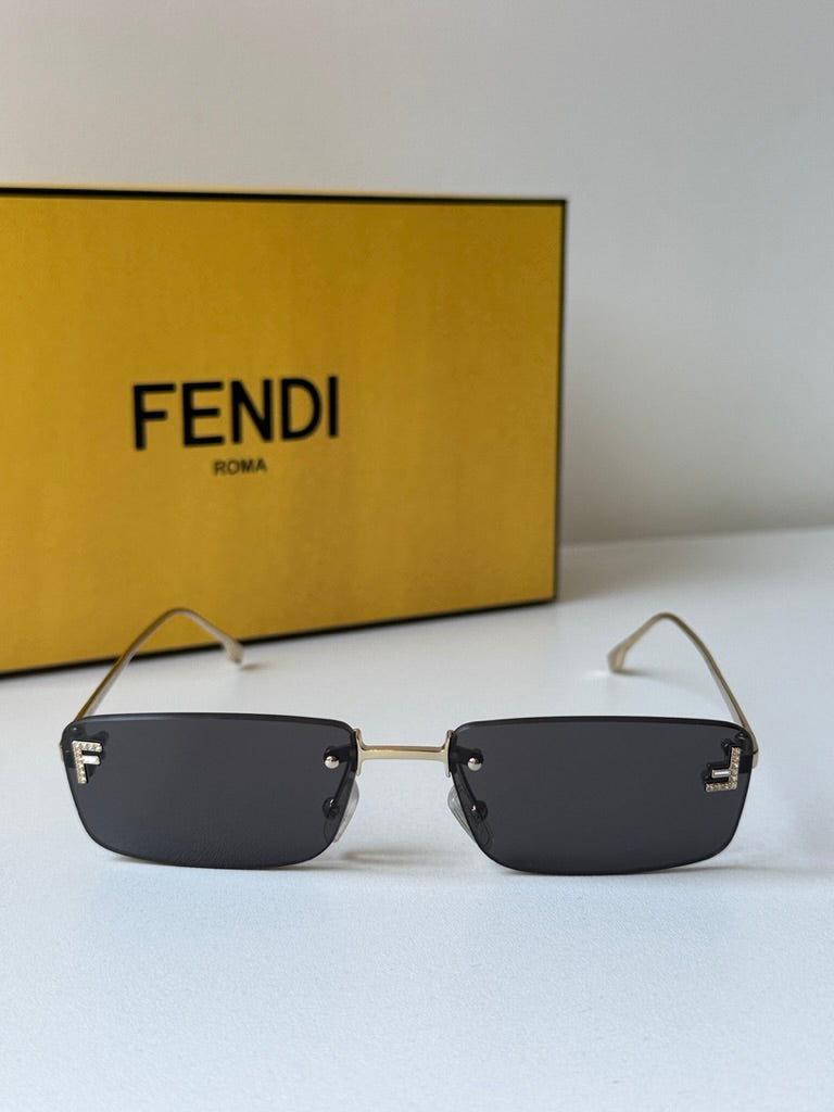 Rimless sunglasses with dark lenses and gold frame, flat square profile