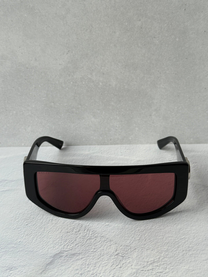 Oversized shield sunglasses with black frame and maroon tinted lenses