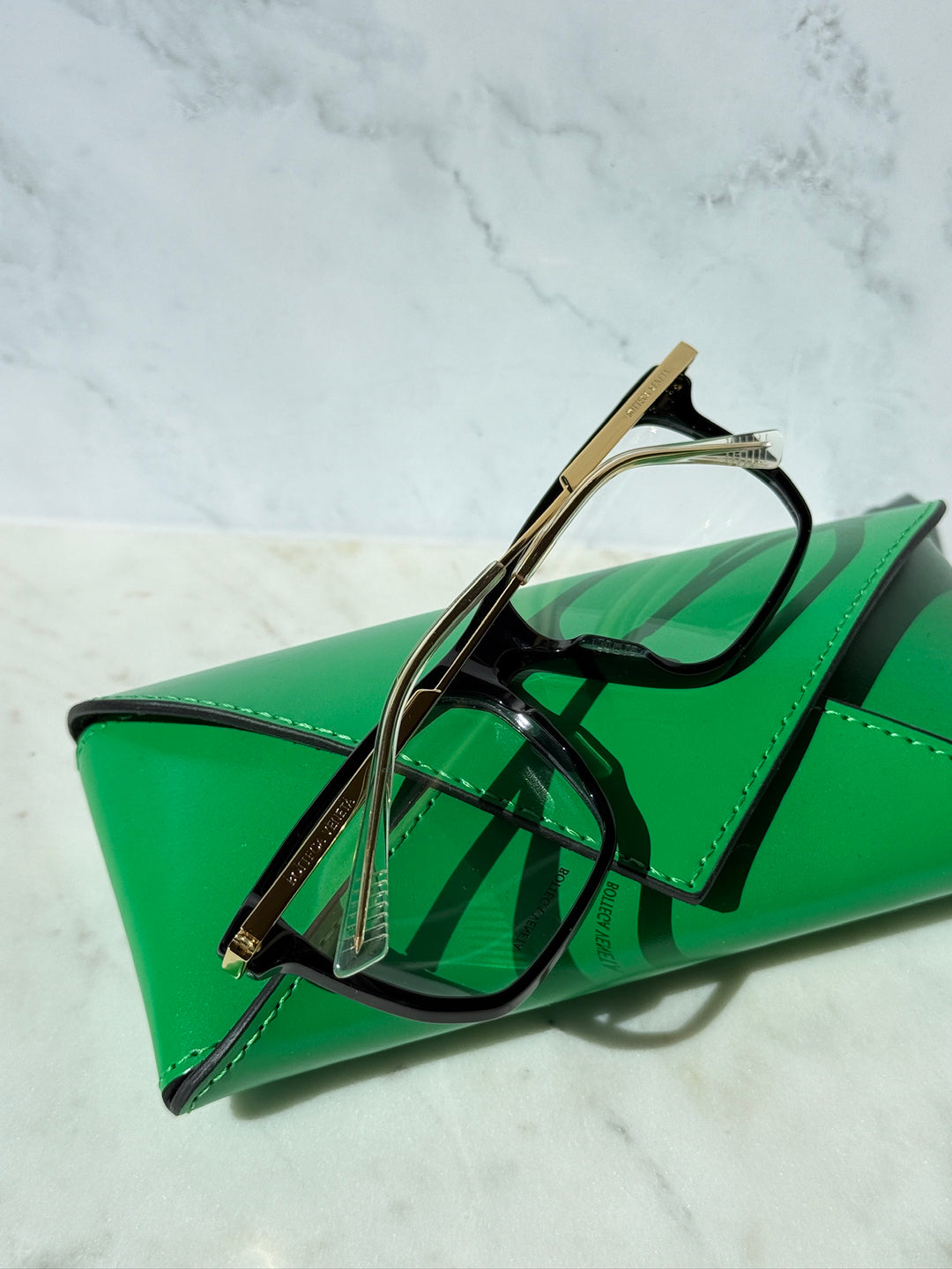 Black eyeglass frames, rectangular lenses, with gold-tone temples, side view.